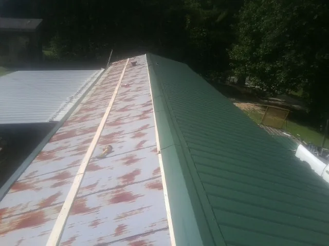 Old rusted panels beside newly installed green metal roofing — Wind Damage Roof Repair by Roofing Brothers in Rollinsville
