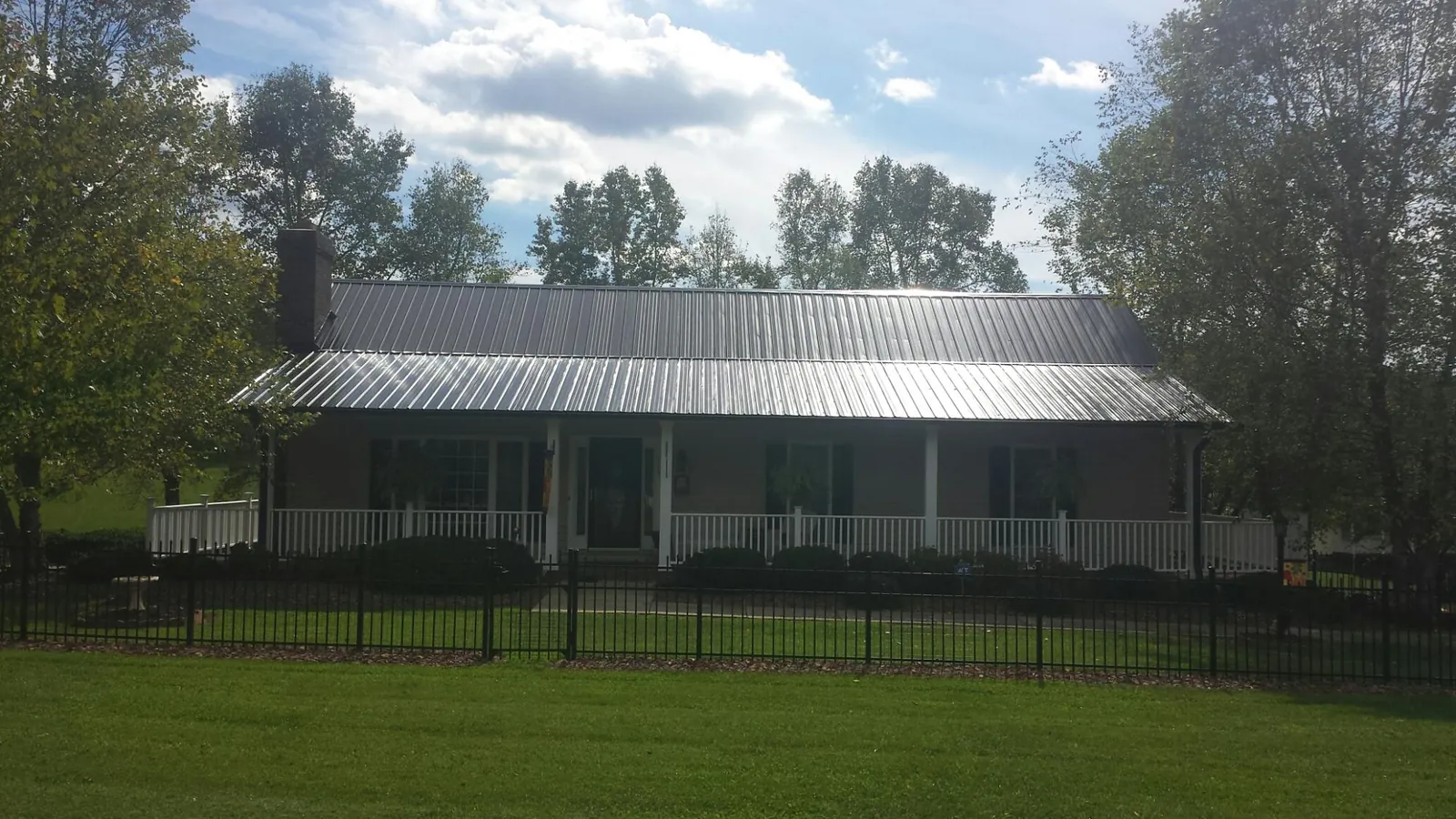 Gray metal roof on a brick ranch with a full width front porch — Gutter Guard Installation work by our crew in Rollinsville
